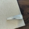 Vista dettagliata di un fermaglio per capelli triangolare in pelle argento con cuciture - Fermaglio Capelli Triangolo Argento Lucido