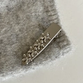 Detail einer silbernen Metall-Haarklammer mit vier kleinen Blumen auf grauem Strick - Silber Dreieck Blumen Stil