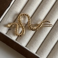 Luxe gouden metalen haarklem in de vorm van een slang met getextureerde details op display - Goud Getextureerde Stijl