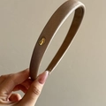 Macro detail of champagne satin headband with gold 'Love' metal emblem texture - Champagne Gold Label