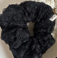 Detailaufnahme eines schwarzen Spitzen-Haargummis mit 3D-Rose und weißem Markenetikett - Schwarze Spitze Blumenstil