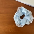 Eleganter hellblauer Satin-Scrunchie mit weißem Spitzenbesatz für Damenfrisuren - Satin-Haargummi mit Spitzenrand / Blau