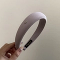 Primer plano de la diadema de tela lila con elegante logo metálico y textura de tejido - Morado