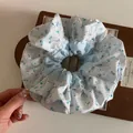 Blumiges Patchwork-Haargummi in Blau und Weiß auf einem eleganten Displayständer - Groß Weiß Blau Blumen Haargummi