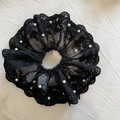 Dettaglio di un elegante elastico in pizzo nero con ricami e accenti di perle bianche - Nero