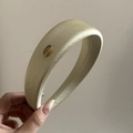 Detail eines hellgrünen Satin-Stirnbands mit einem goldenen Korea-Metall-Etikett - Goldetikett Stil / Hellgelb