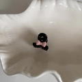 Mini molletta nera con fiocco rosa posata su un piatto in ceramica bianca ondulata - Rosa (4#)