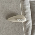 Gros plan sur une pince à cheveux crème sertie de quatre perles sur du lin texturé - Style Goutte d'Eau / Blanc