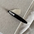Dettaglio di un fermaglio per capelli nero con quattro perle bianche su sfondo di tela - Ovale / Nero