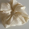 Close-up of a large cream-colored matte fabric scrunchie with soft pleated texture details - Off White