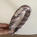 Detail eines rosa-schwarz gestreiften gepolsterten Stirnbands mit handgefertigtem Etikett - Rosa Schwarz Gestreifter Stil