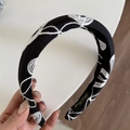 Nahaufnahme eines schwarzen Stoffstirnbands mit weißer Stickerei und goldenem Logo-Detail - Schwarzes Besticktes Stirnband (4# Schwarz-Weiß Texturiertes Stirnband)