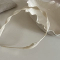 Detalle de diadema de tela acanalada crema con textura en espiral en bandeja - Diadema Retorcida Blanco Roto