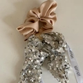 Dettaglio dell'elastico in raso champagne con fiocco di paillettes argento e nastro - Scrunchie Tè al Latte Striscione Paillettes Argento