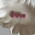 Dettaglio molletta per capelli rosa ondulata in metallo su piatto ceramica - Rosa Rossa