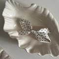 Dettaglio di un fermaglio per capelli in raso a pois neri su un piatto a conchiglia - Fermaglio Fiocco Bianco Pois Neri