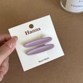 Detail view of two lavender matte oval hair clips displayed on a brand card - Purple