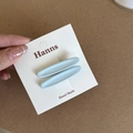 Detail view of two light blue matte oval hair clips set on a white display card - Blue Oval Hair Clip