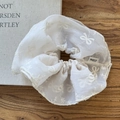 Detail of white mesh scrunchie with bow embroidery and refined stitching on wood surface - White