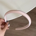 Primer plano detallado de una diadema de satén rosa con textura de tela lisa y suave - Diadema Brillante / Rosa