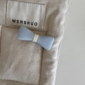 Close-up of light blue fabric bow hair clip with creamy white center on beige canvas - Hair Bow / Blue