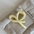 Dettaglio del fermaglio francese bianco crema che mostra la trama e la molla in metallo - Pinza per capelli a croce a Y giallo