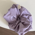 Detail eines hellvioletten Satin-Haargummis mit einem weißen Hand-Made-Webetikett - Glänzendes Haargummi / Lila