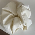 Nahaufnahme von cremeweißem Satin-Haargummi mit glänzender Textur und Falten-Design - Glänzendes Haargummi / Gebrochenes Weiß