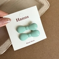 Detail view of mint green bow hair clips on branded card with high gloss finish - Green