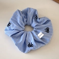 Dettaglio dell'elastico a righe azzurre con fiocchi ricamati neri ed etichetta del marchio - A Righe Blu e Bianche Fiocco Nero