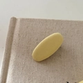 Nahaufnahme der cremegelben Stoff-Haarklammer in Tropfenform auf strukturiertem Hintergrund - 1# Gelbe Ovale Haarspange