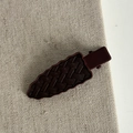 Détail d'une pince à cheveux marron foncé avec texture tressée sur lin neutre - Pince Ondulée sans Trace Bordeaux