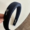 Dettaglio macro del cerchietto in velluto blu navy con ricamo a fiocco bianco ed etichetta - Cerchietto in Velluto Blu Pavone con Segno Bianco