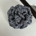 Close-up of a British plaid fabric rose clip with detailed woven petals in vintage colors - Black Striped Flower
