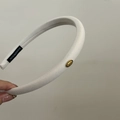 Detail of white textured fabric headband with handmade label and gold love metal tag - White