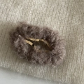 Detalle de pinza de pelo de felpa marrón oscuro sobre un fondo de punto beige - café