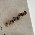 Detail einer s-förmigen Haarklammer mit Leopardenmuster auf Leinenhintergrund - Leopardenmuster Wellen Wassertropfen Haarklammer