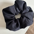 Detail shot of the navy blue textured fabric hair tie with elegant layered pleats and side label - Denim / Navy Blue