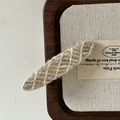 Detailed close-up of a French wool blend hair clip with white mesh texture on linen - Off-white Striped Oval Style