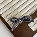 Detalle de pinza para el pelo con lazo de punto gris y emblema metálico de Hand Made - Pinza de Pelo con Lazo de Punto / Gris
