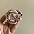 Detailed macro view of a rose velvet flower hair clip with a central pearl bead - Pink