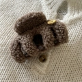 Dettaglio della pinza per capelli in peluche marrone con targhetta dorata su maglia - Cachi