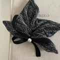 Primer plano de un lazo de tela texturizada negra y plateada con perla decorativa - Estilo Cometa Gris con Perla