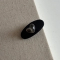 Primer plano detallado del pasador BB de cuero negro con un elegante dije de corazón gris - Estilo Ovalado PU Negro (Corazón)