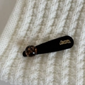 Detalle de pasador de terciopelo negro con esfera de pan de oro sobre tejido blanco - Pinza de Pelo Triangular Negra (Perla Artificial Carey)