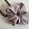 Detail of lilac fabric scrunchie with fine woven texture and premium brand tag - Purple
