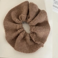 Detail eines weichen dunkelbraunen Strick-Haargummis mit warmer Winterstruktur - Kaffeebraun