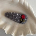 Graue gestrickte Haarspange mit roter Blumenstickerei auf weißem Dekoteller - Grau