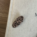 Macro detail of oval leopard print hair clip showing texture on a beige fabric background - Light Leopard Oval Clip