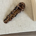 Detail view of stylish leopard print hair clip with wavy edges on soft textured fabric - Leopard Wave Teardrop Clip